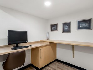 A workspace with a desk, computer monitor, keyboard, and chair. There are three framed pictures on the wall. - Sonesta Simply Suites Detroit Novi (Novi)