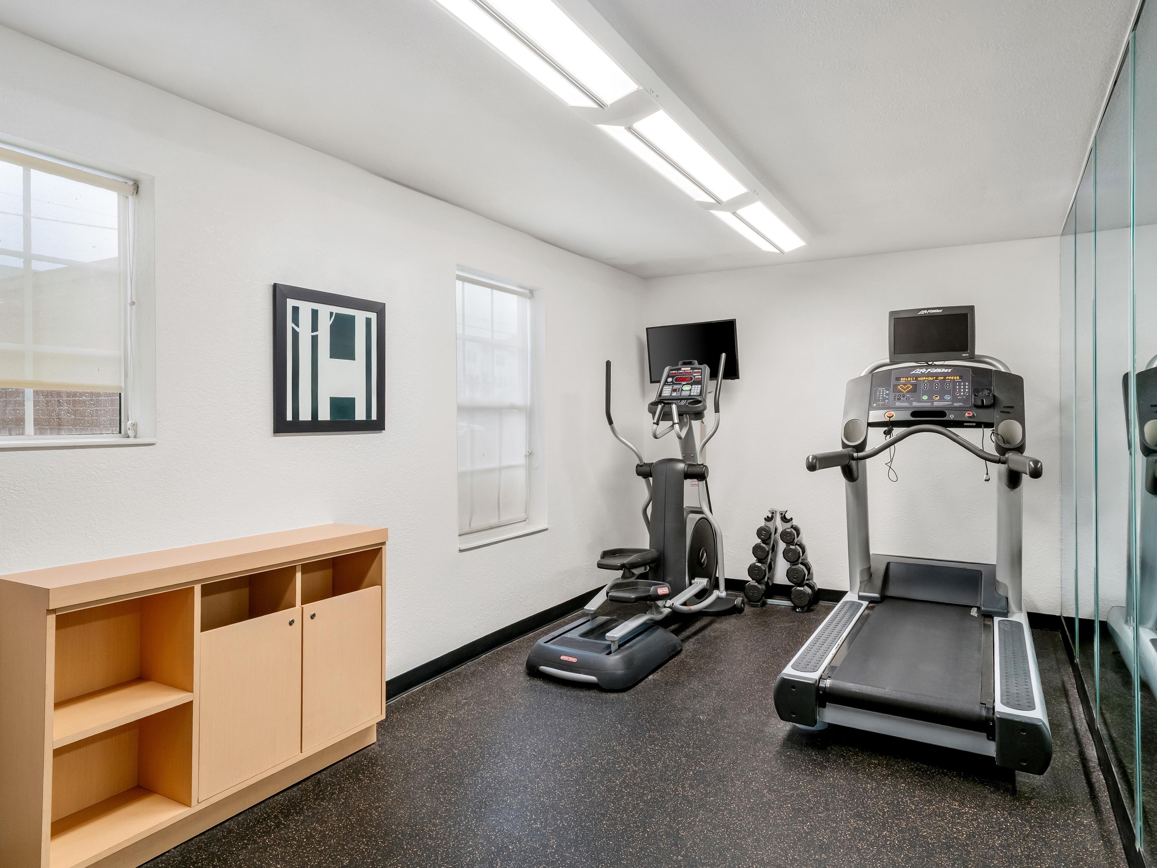 A gym with treadmills, an elliptical, and dumbbells.