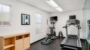 A gym with treadmills, an elliptical, and dumbbells.