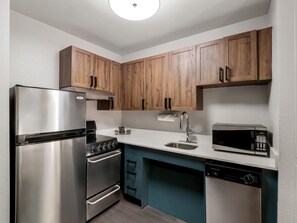 Una cocina moderna con electrodomésticos de acero inoxidable, armarios de madera y un salpicadero verde azulado.