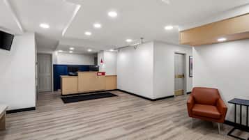 A modern interior with a reception desk, a seating area, and a kitchenette.