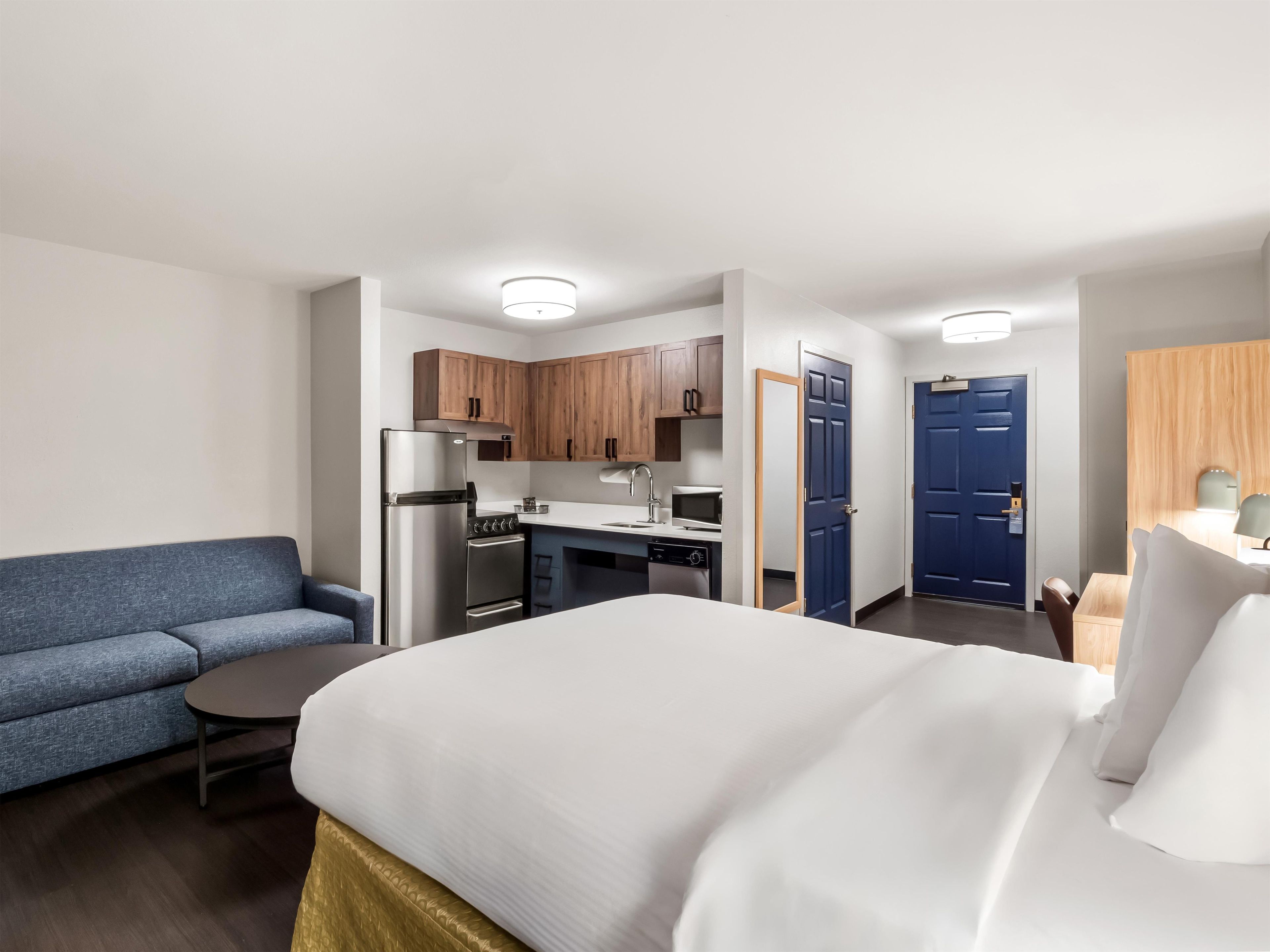 Une chambre d’hôtel comprenant un lit, une petite table, un canapé, un coin cuisine et une salle de bain.