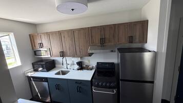 A modern kitchen with wooden cabinets, stainless steel appliances, a microwave, a coffee maker, and a dishwasher.