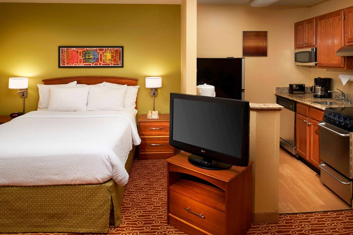 Ein Hotelzimmer mit einem Bett, einem Fernseher, einer Mikrowelle und einer Küchenzeile.