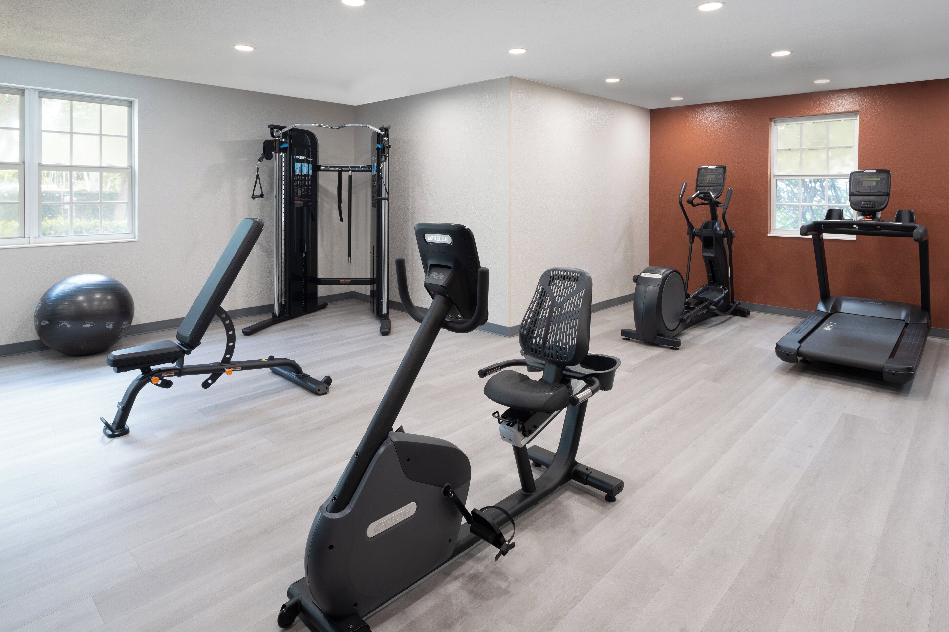 A gym with various exercise equipment including a treadmill, elliptical, and weight machines.