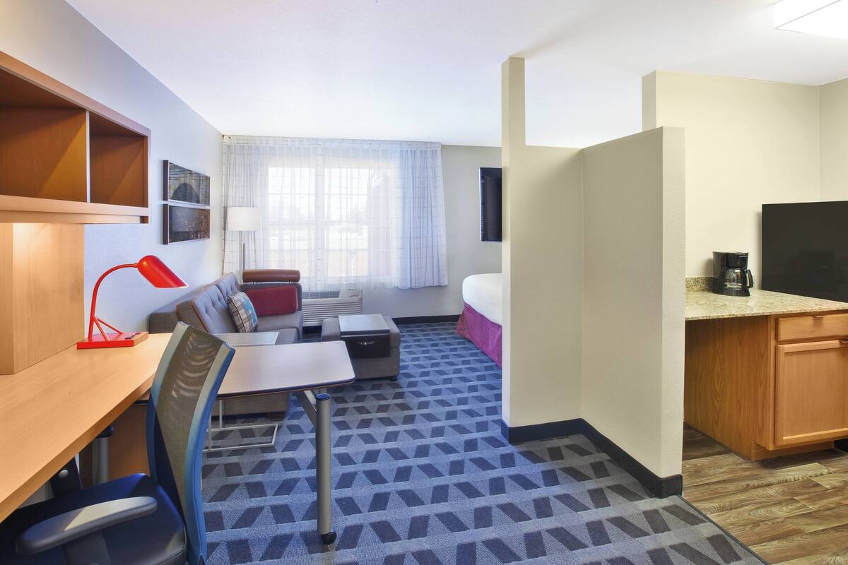 A hotel room with a desk, chair, sofa, and a bed.