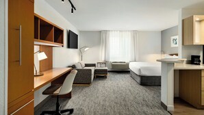 Una habitación de hotel moderna con escritorio, silla, sofá y cama.