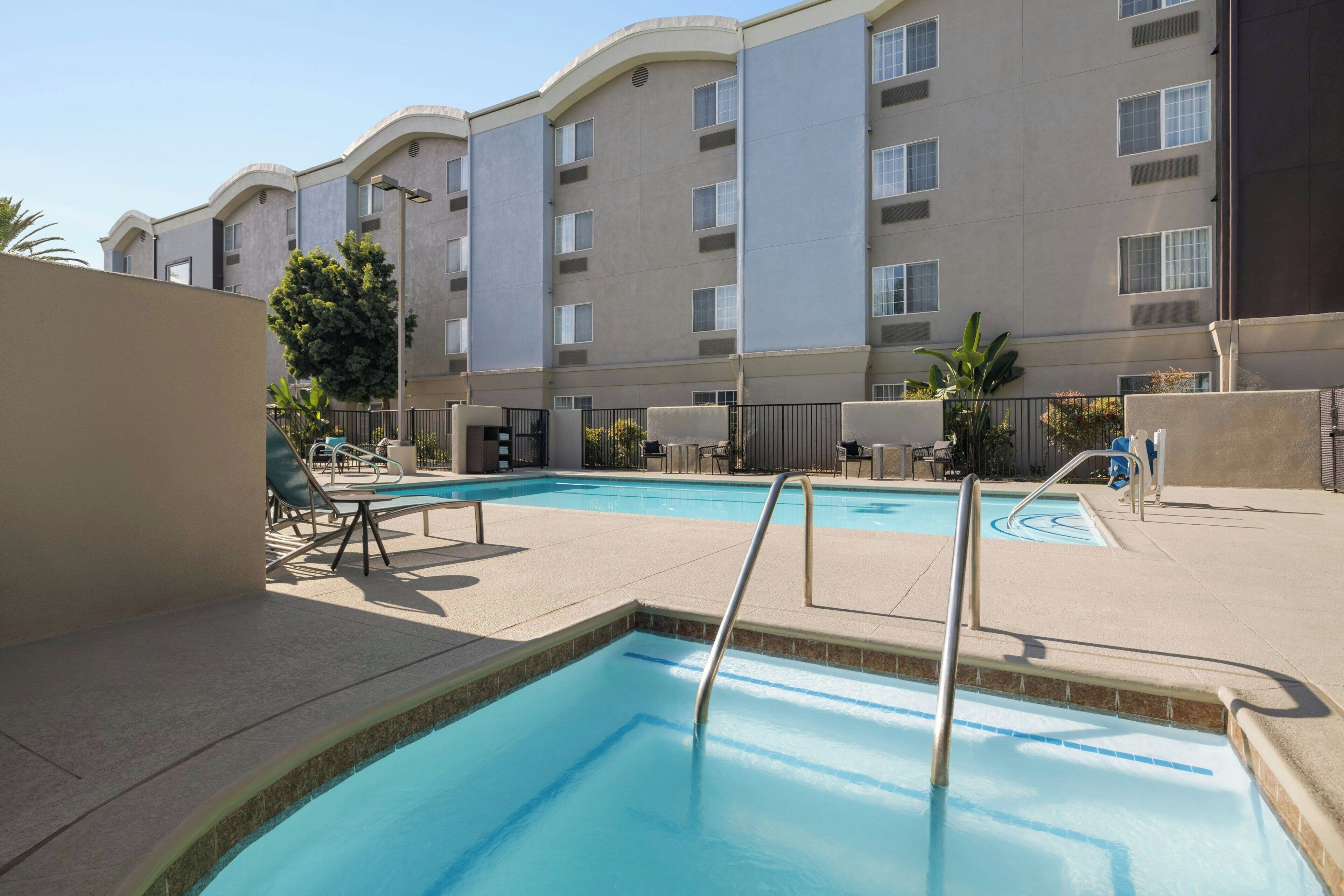 A swimming pool area with lounge chairs and a building in the background.