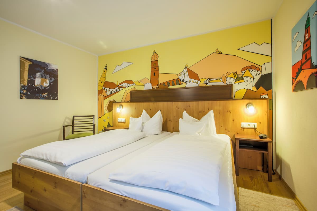 A double bed with white linens, a wooden headboard, and two bedside tables with lamps.