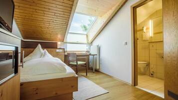 A bedroom with a wooden bed, a desk, and a skylight.