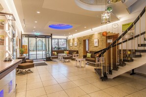 A hotel lobby with a reception desk, seating area, and a staircase. - Hotel Brunner (Amberg)
