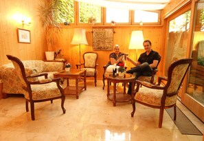Tunnelmallinen huone, jossa on puuseinät, suuri ikkuna sekä oleskelualue, jossa on tuoleja ja pöytä.