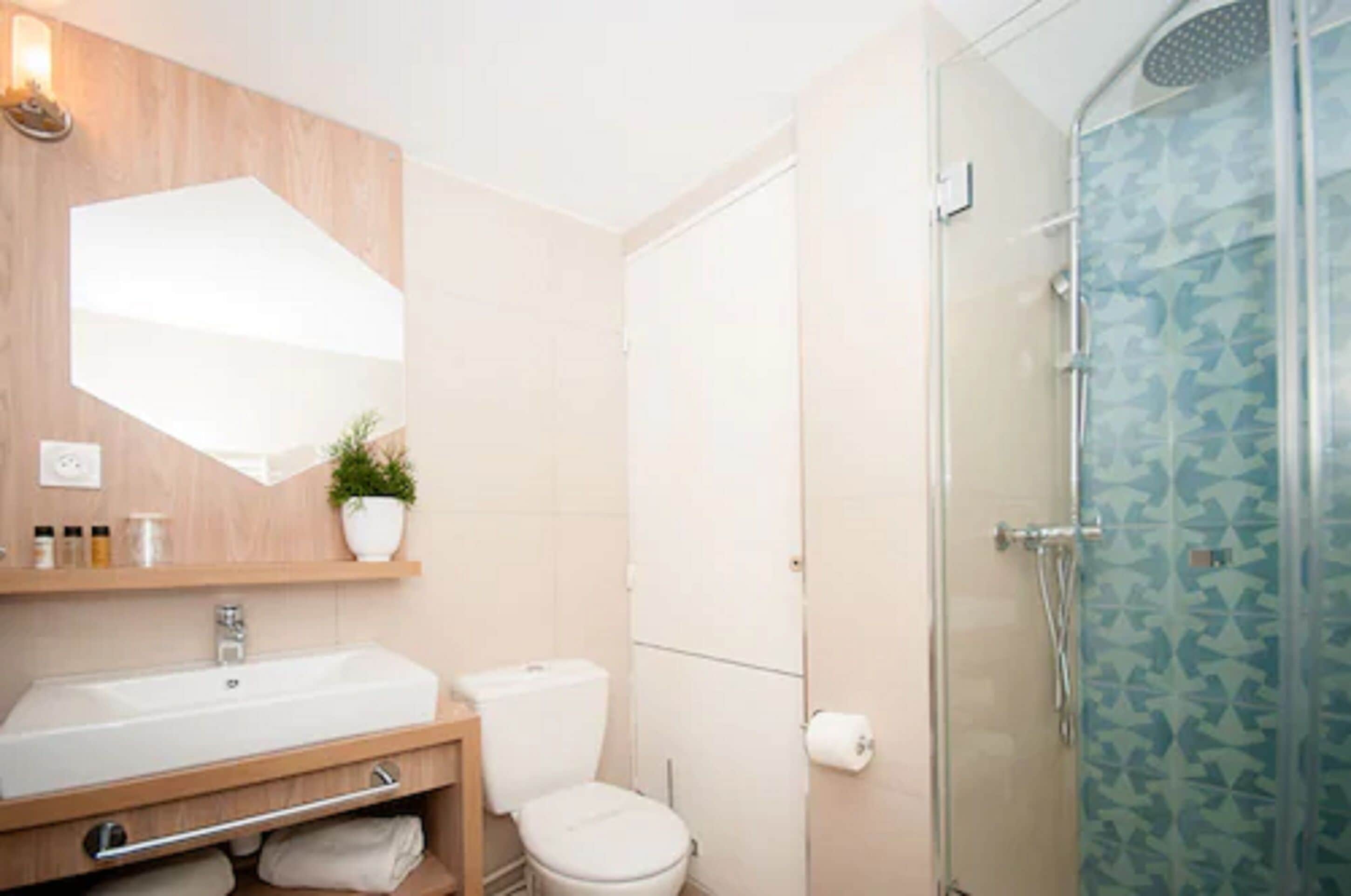 A modern bathroom with a wooden vanity, a toilet, and a glass shower enclosure.