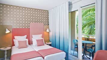 A hotel room with a large bed, two bedside tables, a small round table, and a balcony with chairs.
