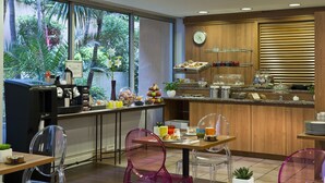 Une cuisine moderne équipée d’une machine à café, d’un présentoir à fruits et de divers produits pour le petit-déjeuner.