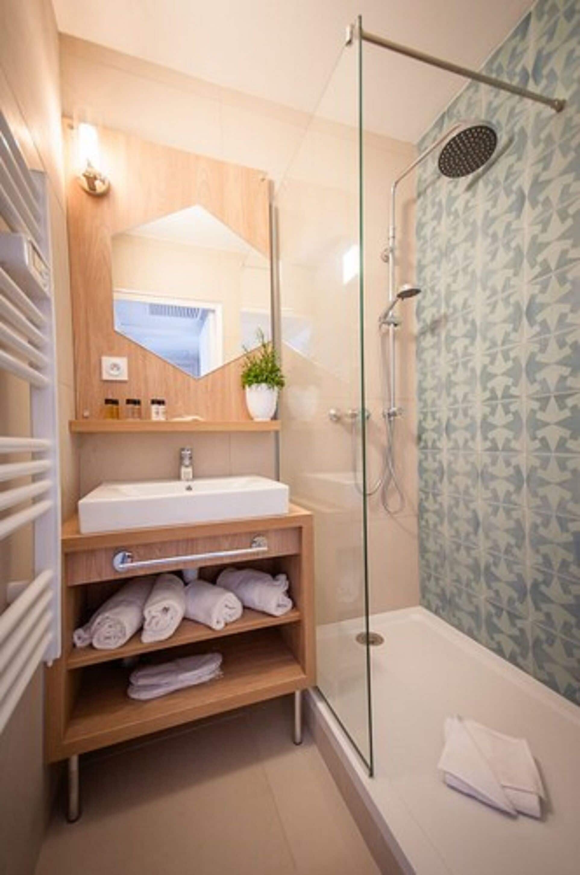 A modern bathroom with a glass-enclosed shower, a wooden vanity with a sink, and a mirror.