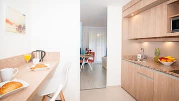 Una cocina moderna con armarios de madera, encimera de granito y comedor con mesa y sillas.