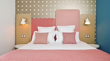 A neatly made bed with a red and white striped headboard, white pillows, and a red patterned bedspread. There are two bedside tables with lamps on either side of the bed.