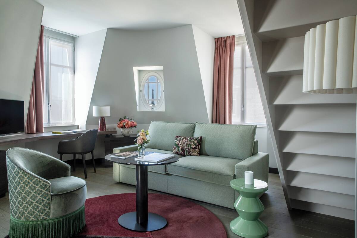 A modern living room with a sofa, armchair, and a small table with a vase.