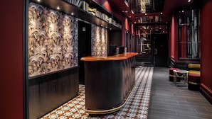A modern interior with a curved reception desk, patterned wall decor, and a tiled floor. - Hotel Indigo Paris - Opera by IHG (Paris)