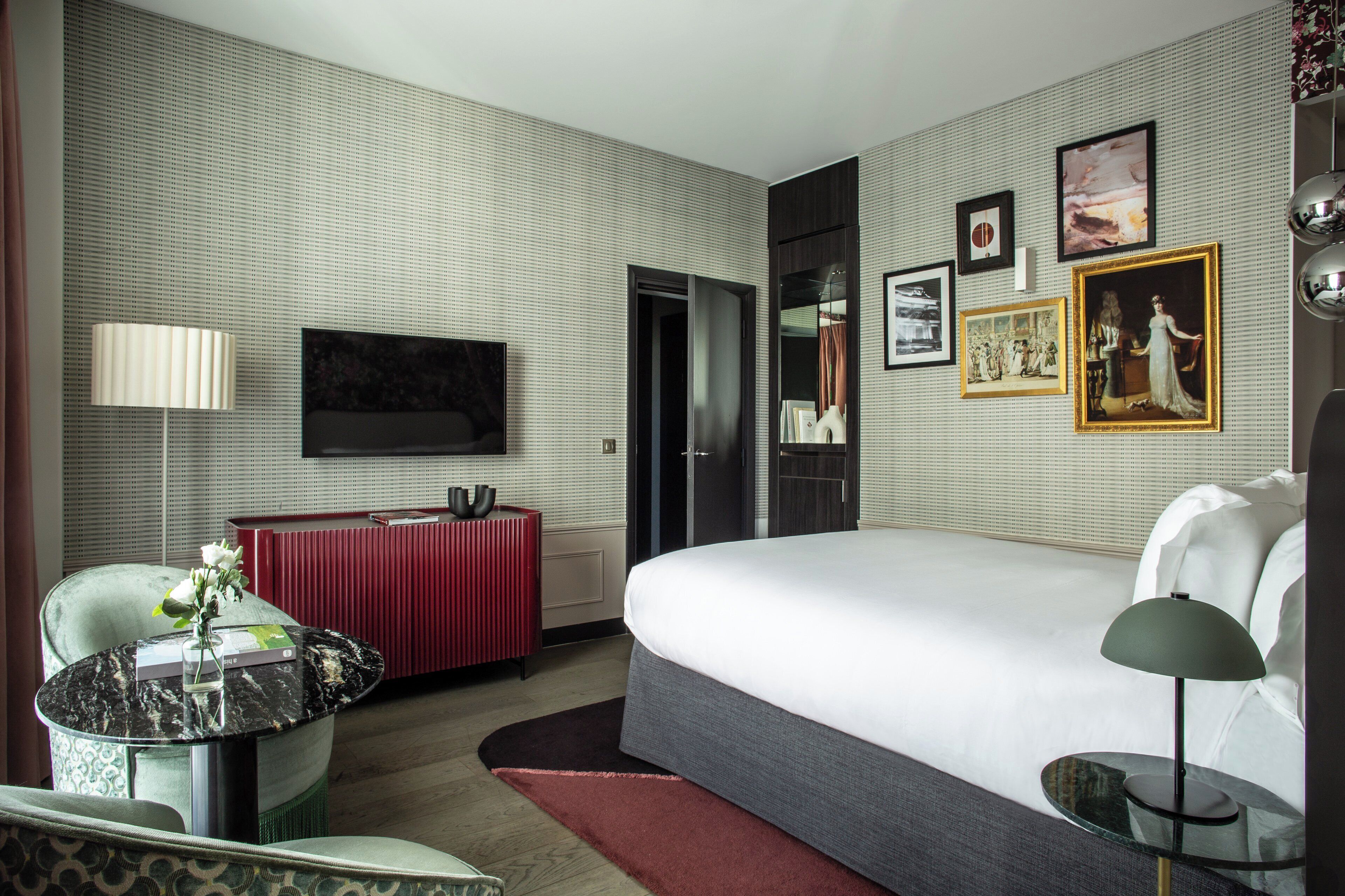 A hotel room with a bed, a TV, a desk, and a chair.