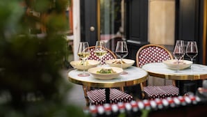 A table set with three bowls of salad and three wine glasses, one with white wine and two with red wine, on a round table with a gold rim. - Hotel Indigo Paris - Opera by IHG (Paris)