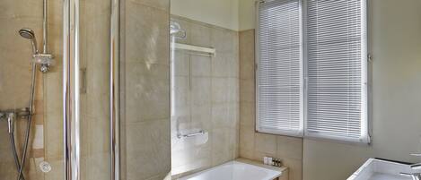 A modern bathroom with a glass-enclosed shower, a freestanding bathtub, and a sink with a mirror.