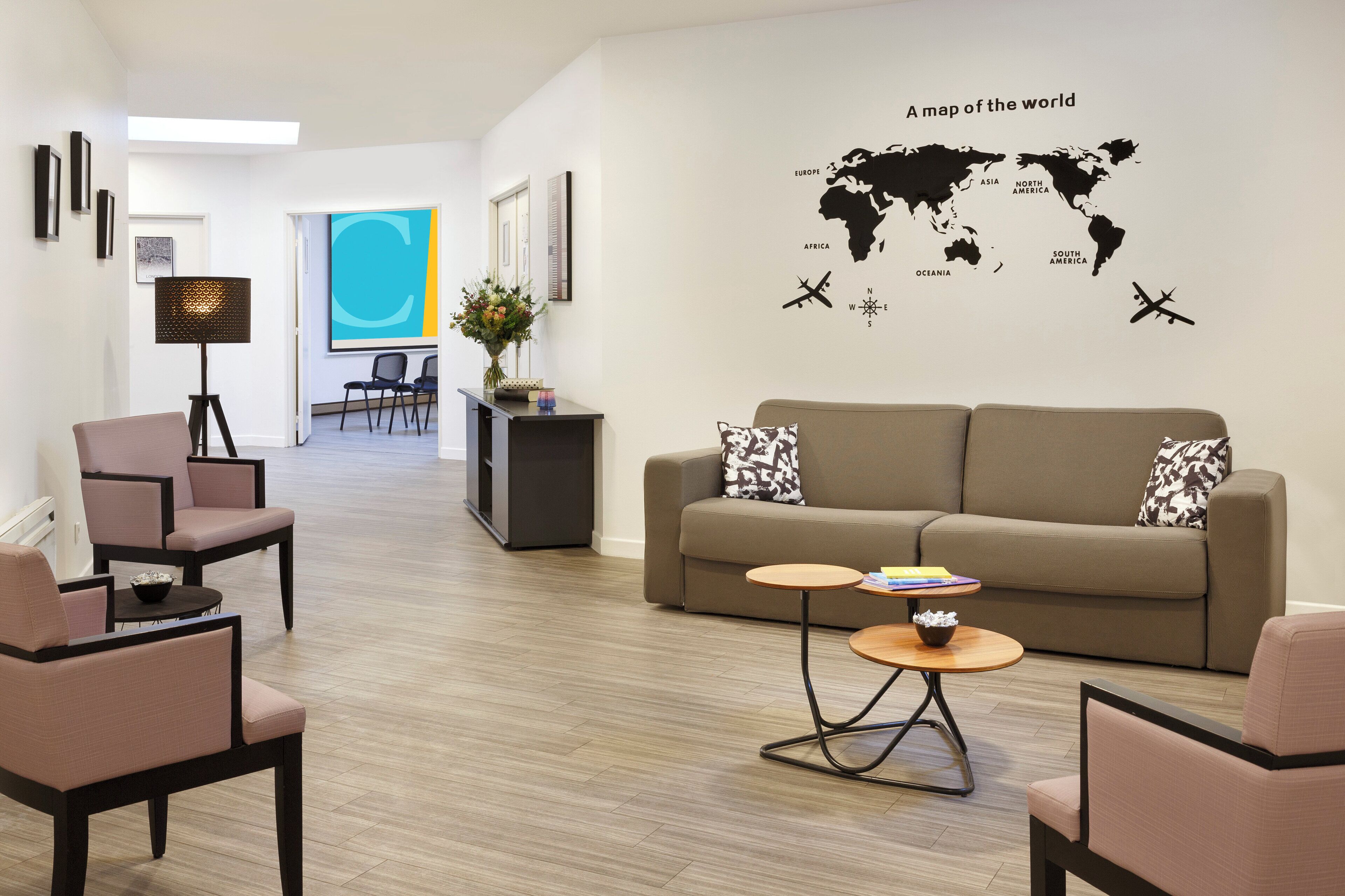 A modern living room with a sofa, chairs, a coffee table, and a world map on the wall.