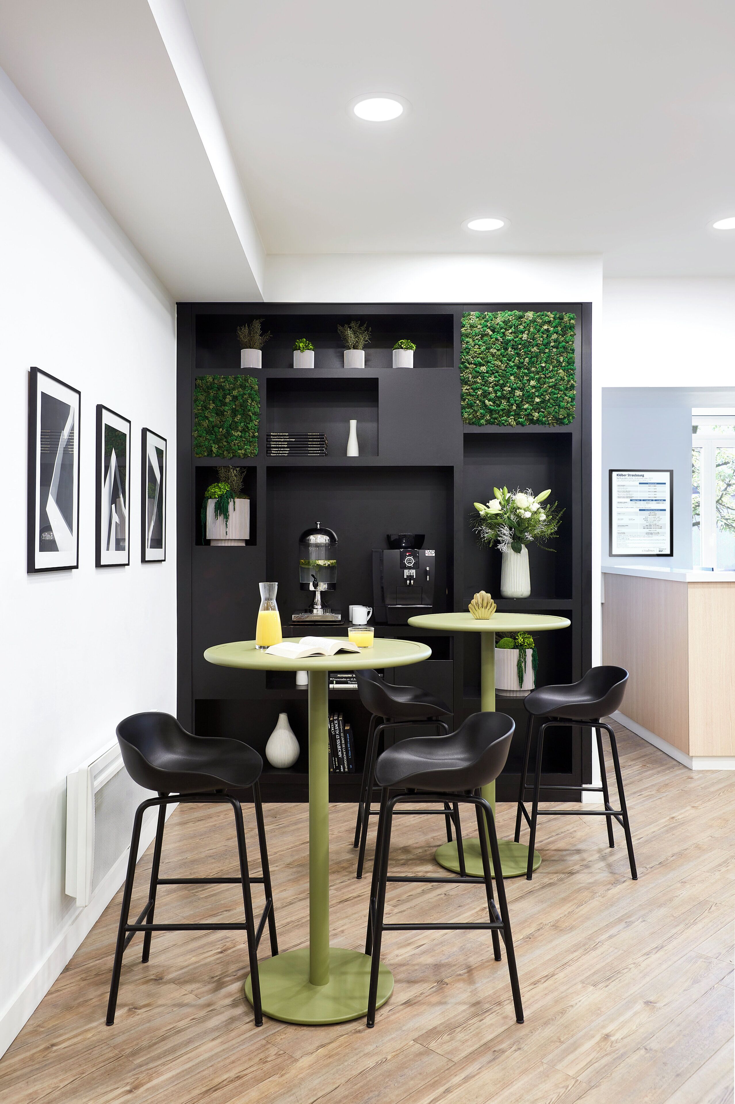 A modern office space with a round table, four chairs, and a coffee machine.