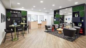 A modern office space with a reception desk, seating area, and shelves with plants. - Citadines Kléber Strasbourg (Strasbourg)