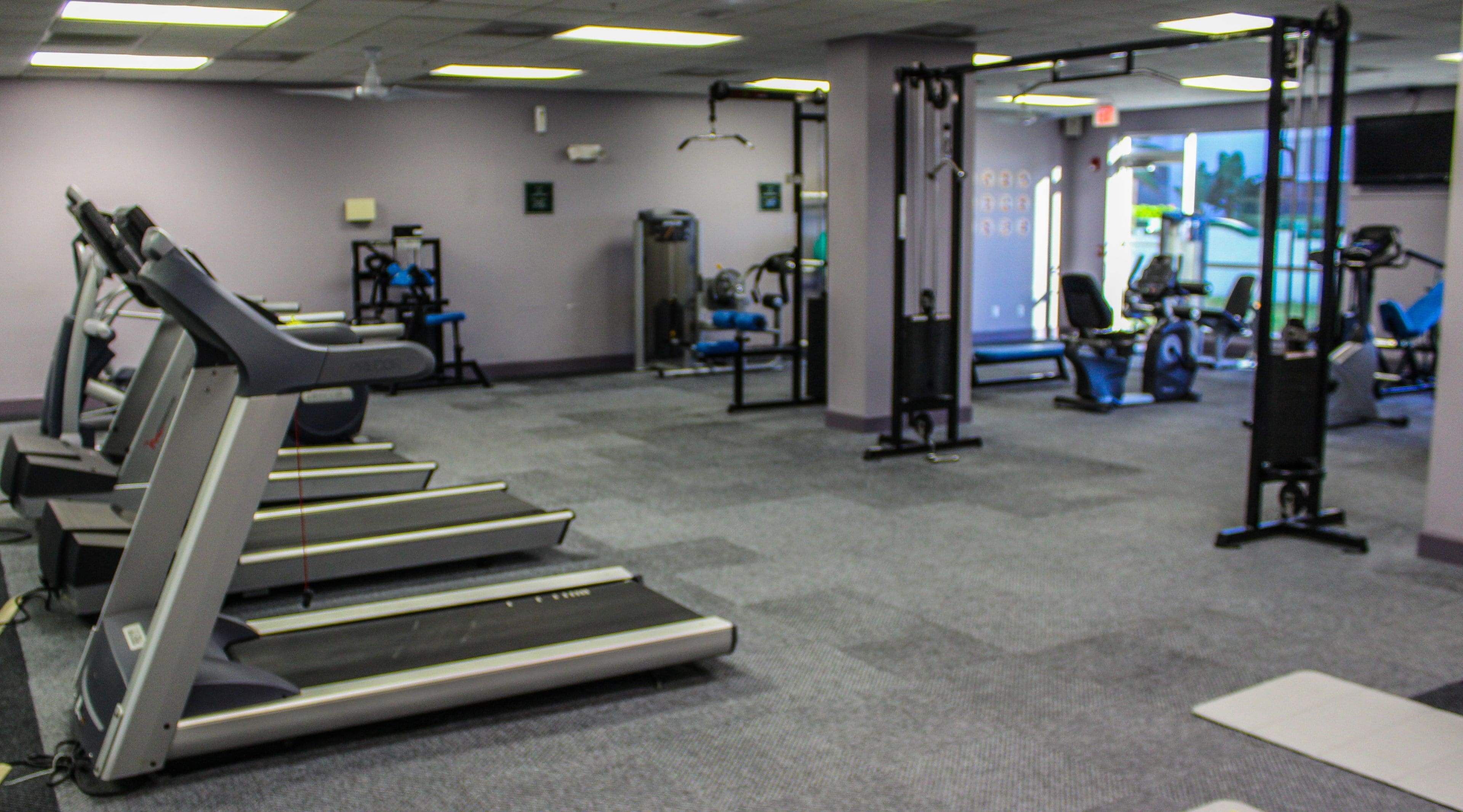 Une salle de sport équipée de tapis de course, d’appareils de musculation et d’autres équipements d’exercice.