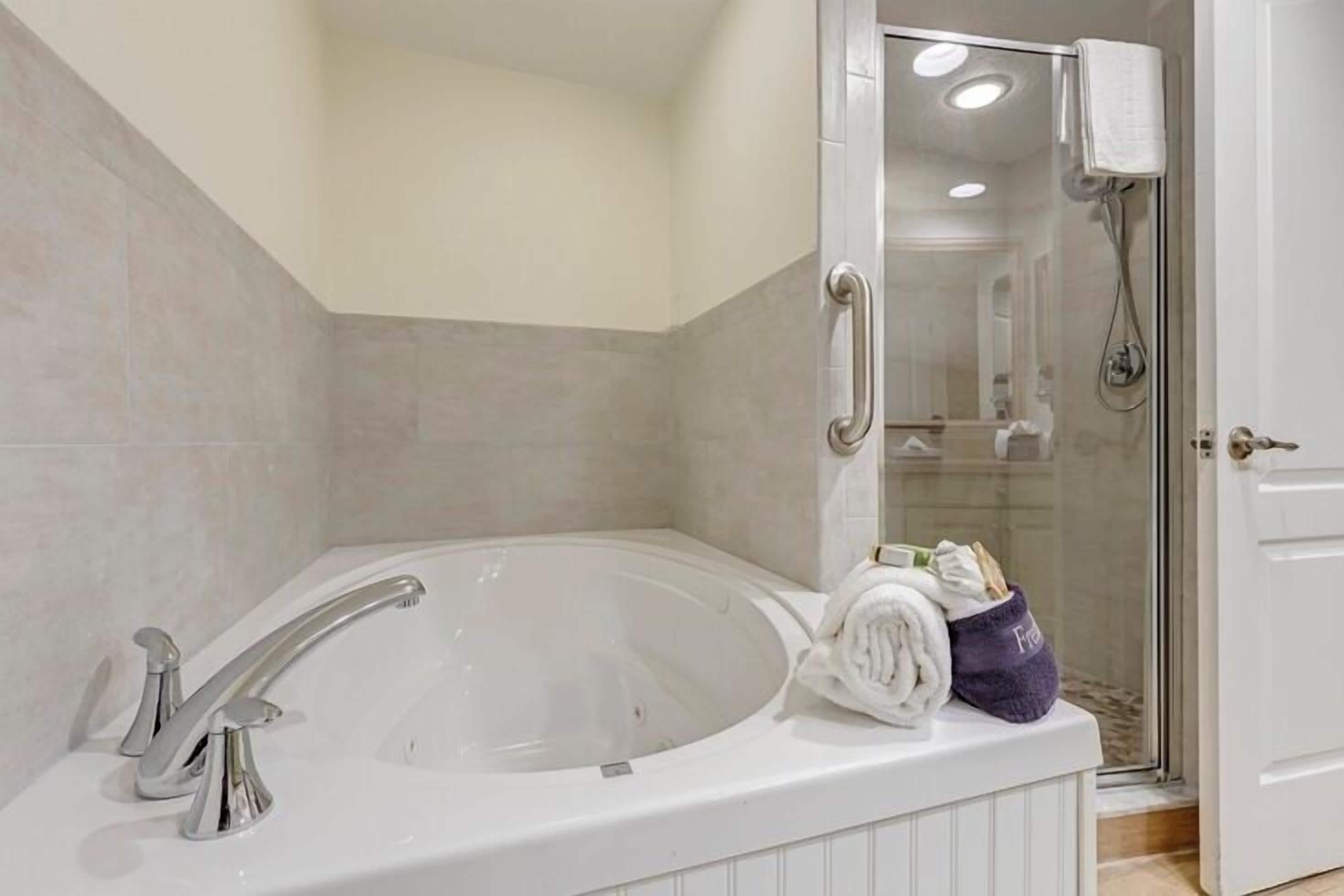 Un baño con una bañera grande, ducha y zona de ducha con mampara de vidrio.