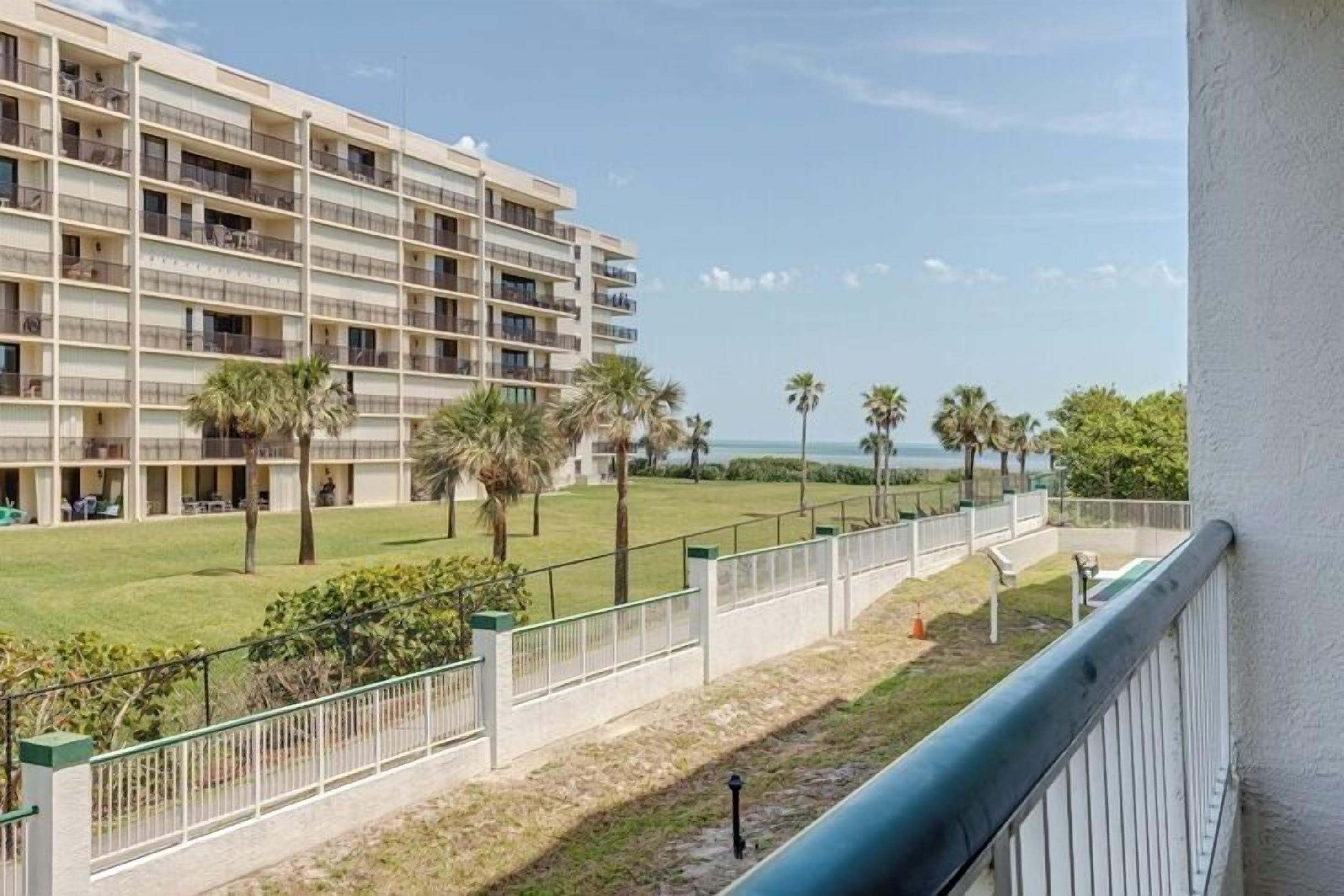 Un hôtel à plusieurs étages doté de balcons, d’une pelouse verdoyante et de palmiers.