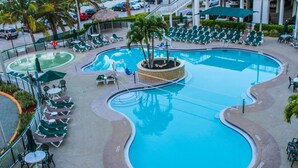 A large, multi-level swimming pool with various seating areas and palm trees. - The Resort on Cocoa Beach (Cocoa Beach)
