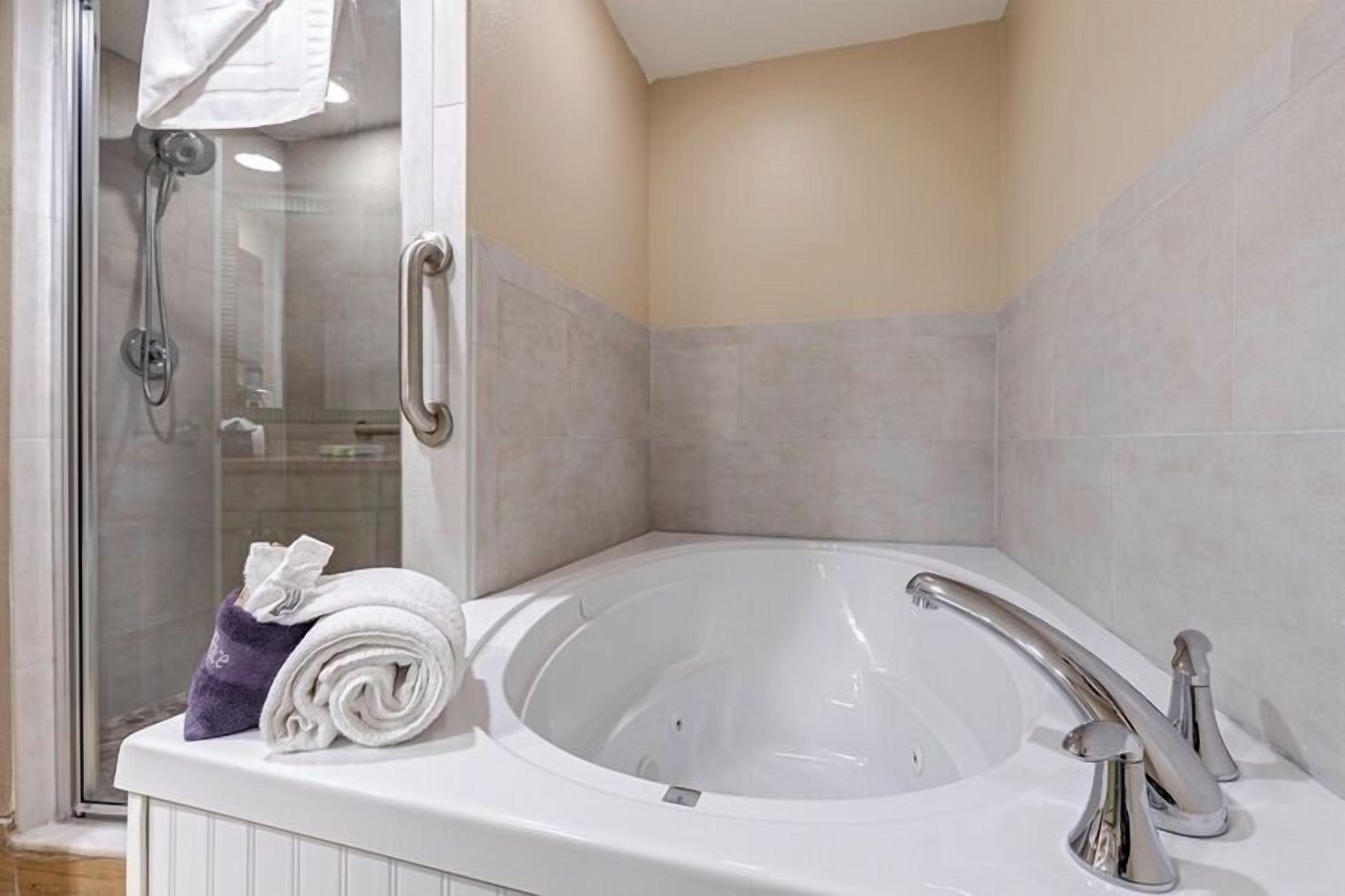Un baño moderno con una bañera grande, cabina de ducha de vidrio y un perchero para toallas.