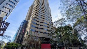 Un edificio alto y moderno con fachada curva, múltiples ventanas y banderas.