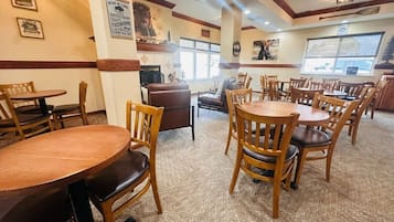 Interior de restaurante con mesas y sillas de madera, una chimenea y cuadros en las paredes.