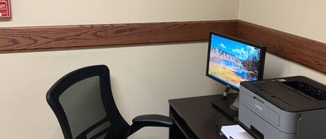 A home office setup with a computer monitor, printer, and office chair.