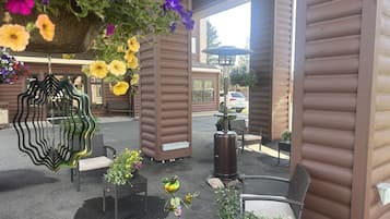 Un espacio de estar al aire libre cubierto, con mobiliario de mimbre y cestas de flores colgantes.