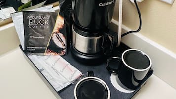 Una cafetera con una bandeja, dos tazas, un libro y un enchufe.