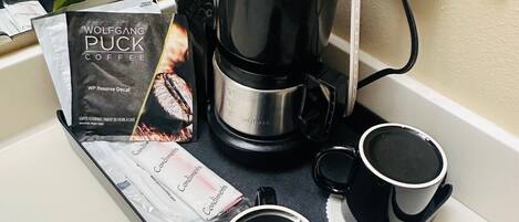 Una cafetera con una bandeja, dos tazas, un libro y un enchufe.