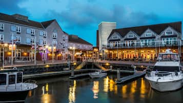A waterfront hotel with a dock, a bridge, and a modern building in the background.