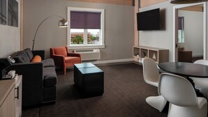 Una sala de estar moderna con sofá, sillón, reposapiés y una mesa de comedor.