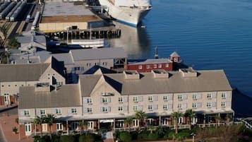 A large hotel with a parking lot and a cruise ship docked nearby.