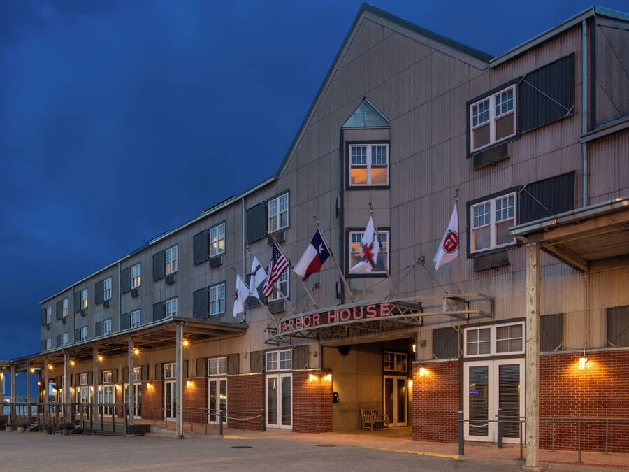 Een hotel met meerdere verdiepingen, een opvallende ingang, diverse vlaggen en een overdekt terras met zitplaatsen.