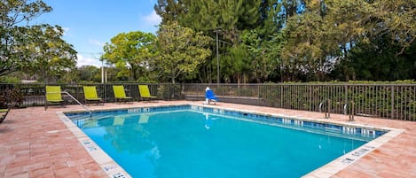 A rectangular swimming pool with a tiled edge, surrounded by a brick deck.