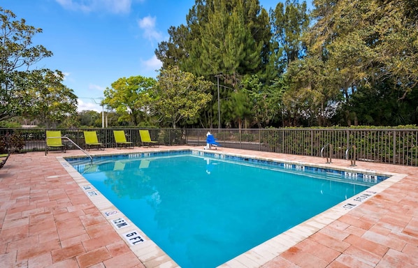 A rectangular swimming pool with a tiled edge, surrounded by a brick deck.