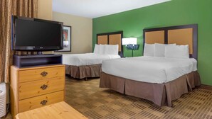 Une chambre d’hôtel avec deux lits, une télévision, une commode et un sol recouvert de moquette.