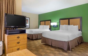 A hotel room with two beds, a television, a dresser, and a carpeted floor.