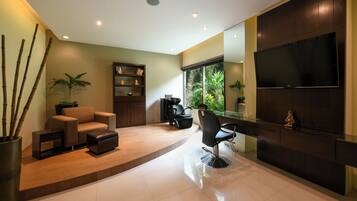 Una sala de estar moderna con un sofá, un sillón y un televisor montado en la pared.